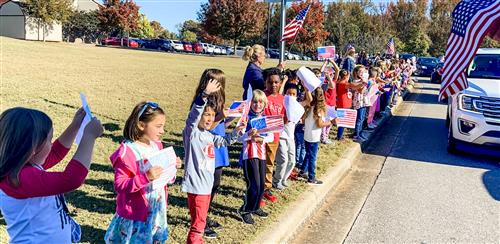 wide angle view of students and teachers lining parade route at school